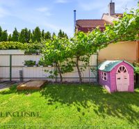 The garden of a family house in Gabčíkovo with a sandbox and a children's playhouse on the grass.