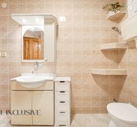 A bathroom in a family house with a white sink and mirror, light tiles.