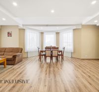 Living room with a sofa, dining table, and wood-patterned flooring in a family house.