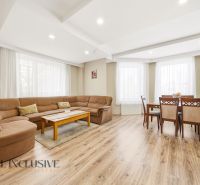 Living room with a large sofa, dining table, and floor with a wooden decor.