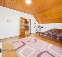 A bedroom in a family house with a wood-patterned floor, a bed, and a desk.