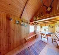 Interior of a cabin with wooden wall paneling, benches, and a floor with a wood decor.