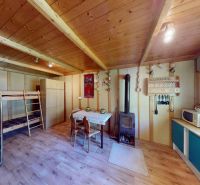 The interior of a cabin with a bunk bed, table, stove, and floor with a wooden decor.