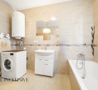 Bathroom in a 3-room apartment with a washing machine, bathtub, and beige tiles.