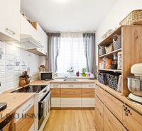A kitchen with appliances and shelves in a 3-room apartment with a wooden decor floor.