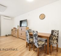 Dining nook in a 3-room apartment with decorative furniture and wood-patterned flooring.