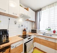 A kitchen with appliances, curtains, and a wooden decor floor in a 3-room apartment.