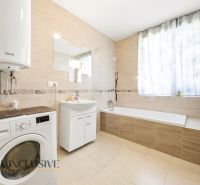 A spacious bathroom with a bathtub and a washing machine in a 3-room apartment.
