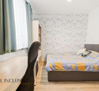 Bedroom in a 3-room apartment with a wooden decor floor, a table, and a bed.