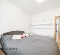 A bedroom in a 3-room apartment with a large bed and a floor with a wood decor.