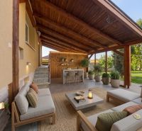 The terrace of a family house in Báč with wooden paneling, seating, and garden plants.