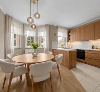 A kitchen in a family house with a wooden decor floor, a round table, and pendant lights.