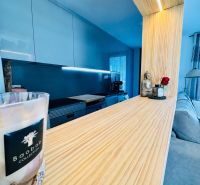 A kitchen unit in a 3-room apartment with a wooden decor floor and modern lighting.