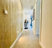 A hallway in a 3-room apartment with a textured wall and tiled floor.