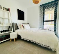 Bedroom in a 3-room apartment with a bed, white shelf, and window with blinds.