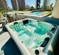 Hot tub on the terrace of a 3-bedroom apartment in Calpe, overlooking the pool and high-rise buildings.