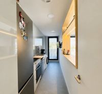 A narrow kitchen in a 3-room apartment with modern equipment and a gray floor.