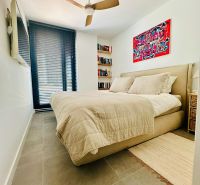 Bedroom in a 3-room apartment with a fan, bed, and art on the wall.