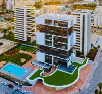 A building with a garden and a pool in Calpe, adjacent to many other buildings.