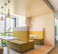 Dining in an office with a wooden floor decor and a view of a tall building.