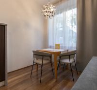 Dining area with a table and two chairs, wooden decor flooring, pendant light.