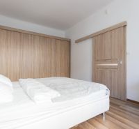 Bedroom in a 2-room apartment with a bed and wardrobes, floor with wooden decor.