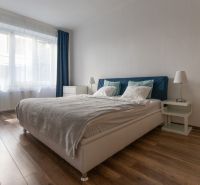 Bright bedroom with a bed and an office chair in a 2-room apartment, floor with wooden decor.