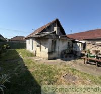 A courtyard of a family house in Šurany with a smaller older house and a table for sitting.