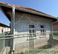A family house in Šurany with white windows and a red roof behind a fence.