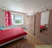 A bedroom with red bedding, a wardrobe, and a wooden decor floor in a two-room apartment.