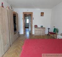 A room in a 2-room apartment with a bed, a floor with a wooden decor, and a wardrobe.