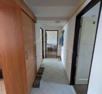 A hallway in a 2-room apartment with tiles and a floor cabinet with a wooden decor.