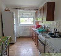 A kitchen in a 2-room apartment with ceramic tiles and a wooden decor floor.
