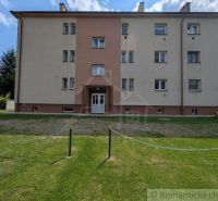 An apartment building in Medzilaborce with a green courtyard, three stories, and bright facades.