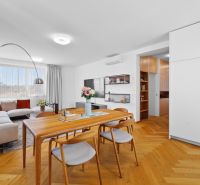 Bright living room with wood-patterned flooring and a comfortable corner sofa.