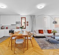 Bright kitchen and living room in a 4-room apartment with a wooden decor floor and a comfortable couch.