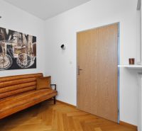 Entrance hall with a brown sofa, a painting, and a floor with a wooden decor in a 4-room apartment.