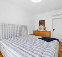 Bedroom with a patterned bed, paintings, and a dresser in a 4-room apartment, floor with wooden decor.