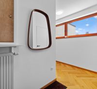 Mirror, radiator, and window in a 4-room apartment with a wooden decor floor.