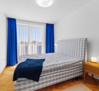 A bright bedroom with a patterned bed in a 4-room apartment with wood-patterned flooring.