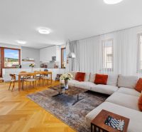 Living room in a 4-room apartment with a wooden decor floor, a large sofa, and a dining table.