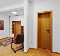 A hallway in a 4-room apartment with a wooden decor floor, a painting, and a comfortable armchair.