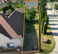 A plot of land in Topoľníky next to a family house with trees and a road.