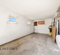 A spacious garage in a family house with white walls and small windows.