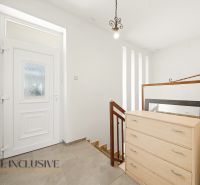 A hallway in a family house with white walls, doors, and a cabinet.