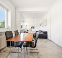 Dining area in a family house with black chairs and a large window.