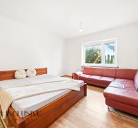 A bedroom in a family house with a wooden decor floor, a red sofa, and a bed.