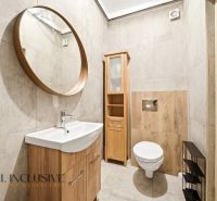 Bathroom in a family house with a round mirror and wooden decor on the walls.