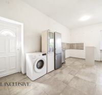 A kitchen in a family house with a washing machine and a refrigerator on the tiles.