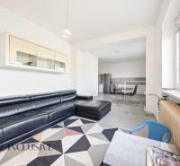 Living room in a family house with a black sofa and a dining area.